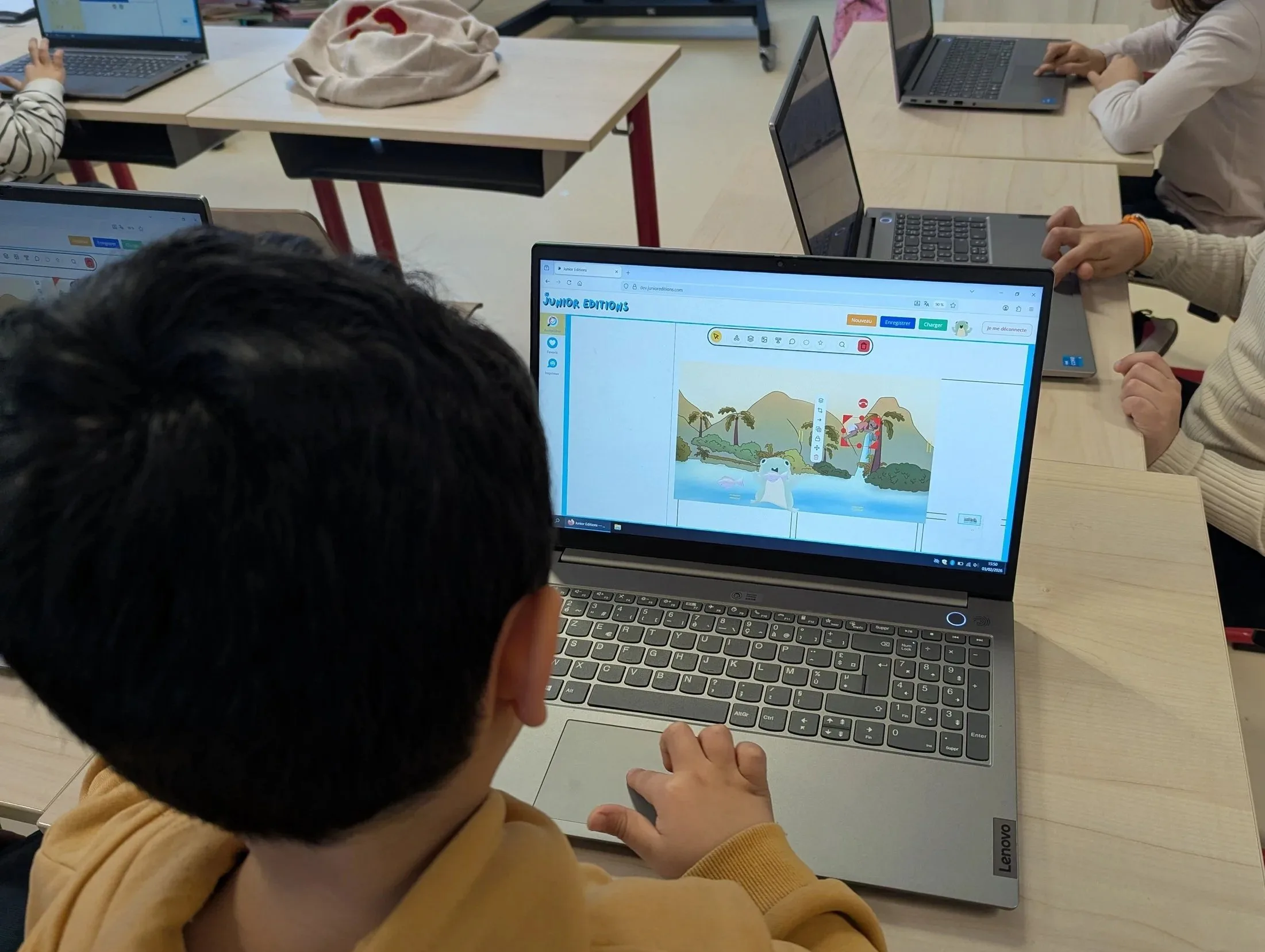 A child sitting in front of a laptop, using the children’s platform called 'Junior Éditions'.